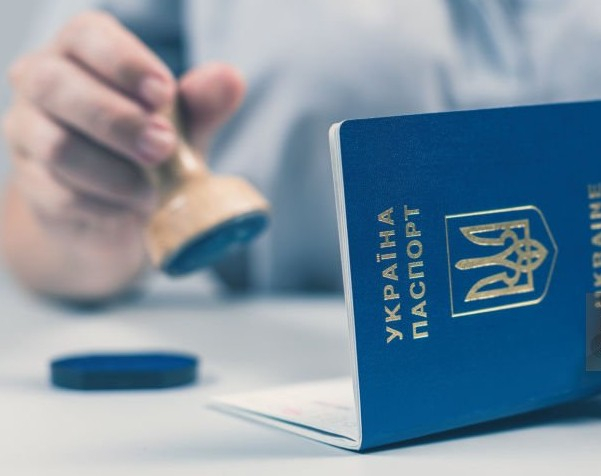 dłoń trzymająca stempel pieczęci wraz z uraińskim paszportem